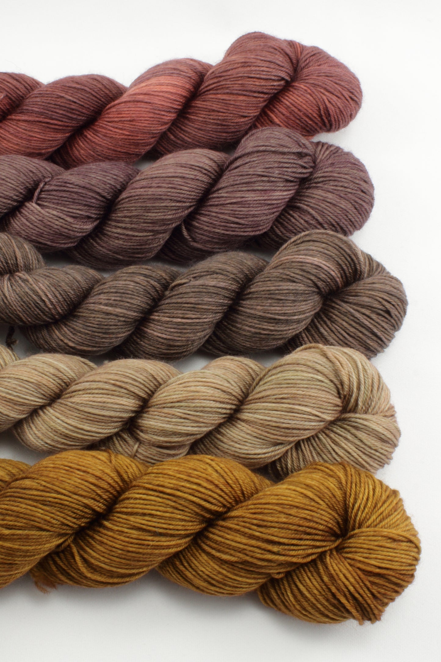 Set of yarn skeins in brown and red tones on a white background