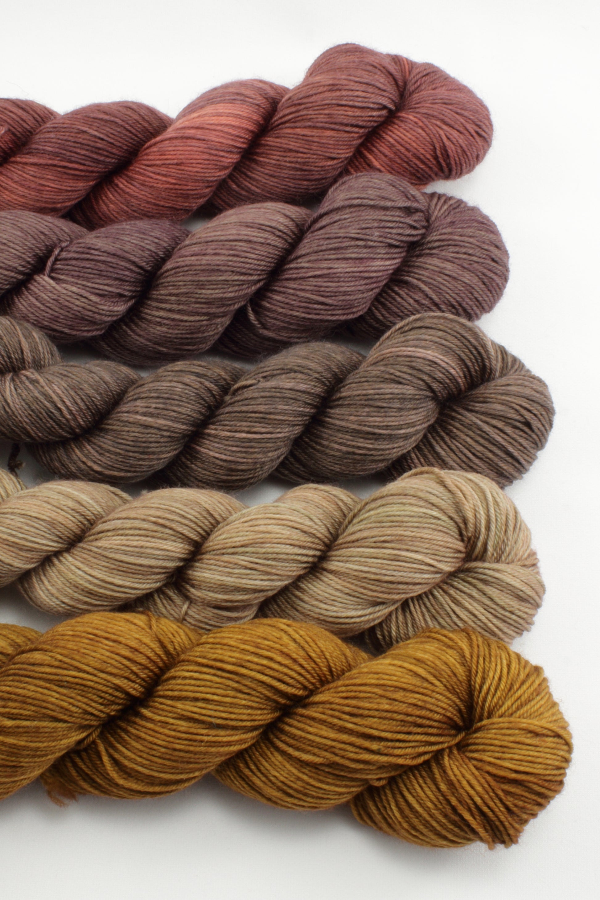 Set of yarn skeins in brown and red tones on a white background
