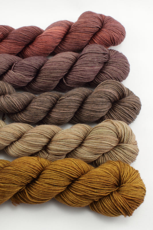 Set of yarn skeins in brown and red tones on a white background